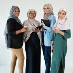 A group of diverse Muslim women in hijabs working together in an office setting.