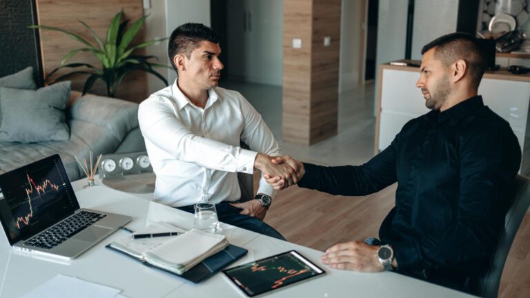 Two men shaking hands in an office, symbolizing successful agreement or partnership.