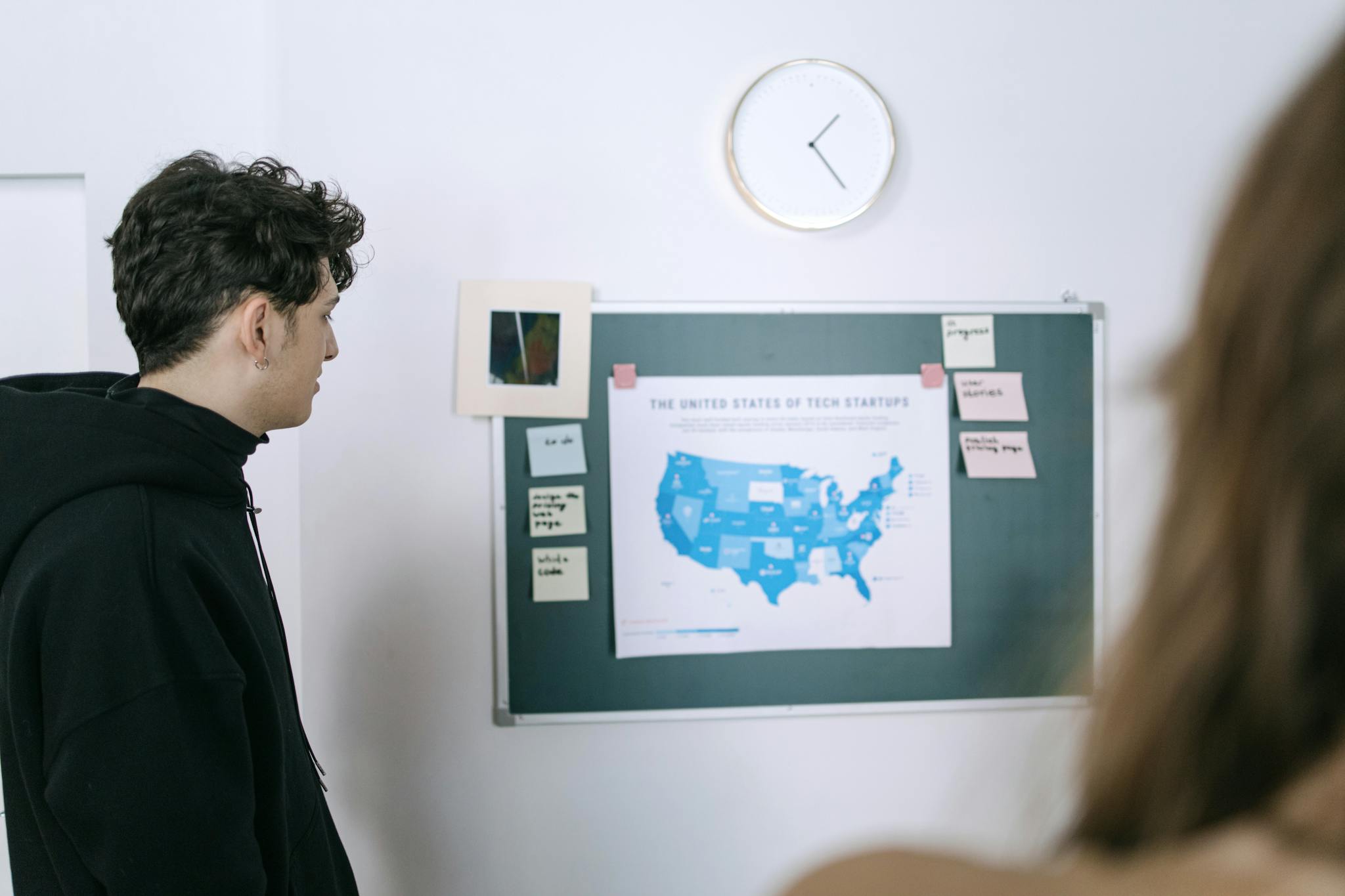 Young professionals discussing a map of US tech startups in a modern office setting.